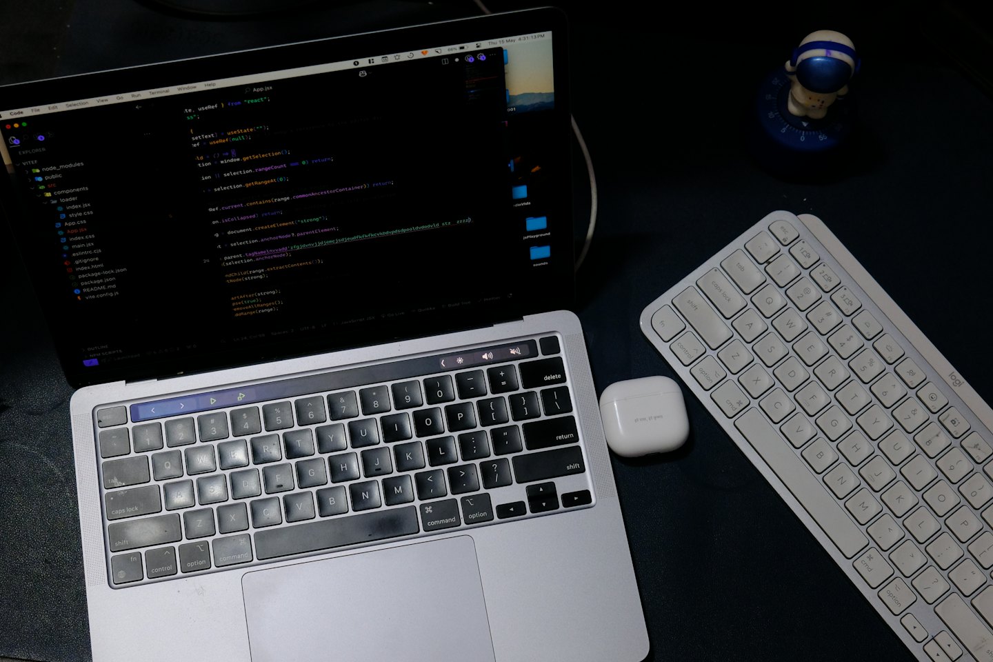 A laptop showing code sits on a desk with keyboard.